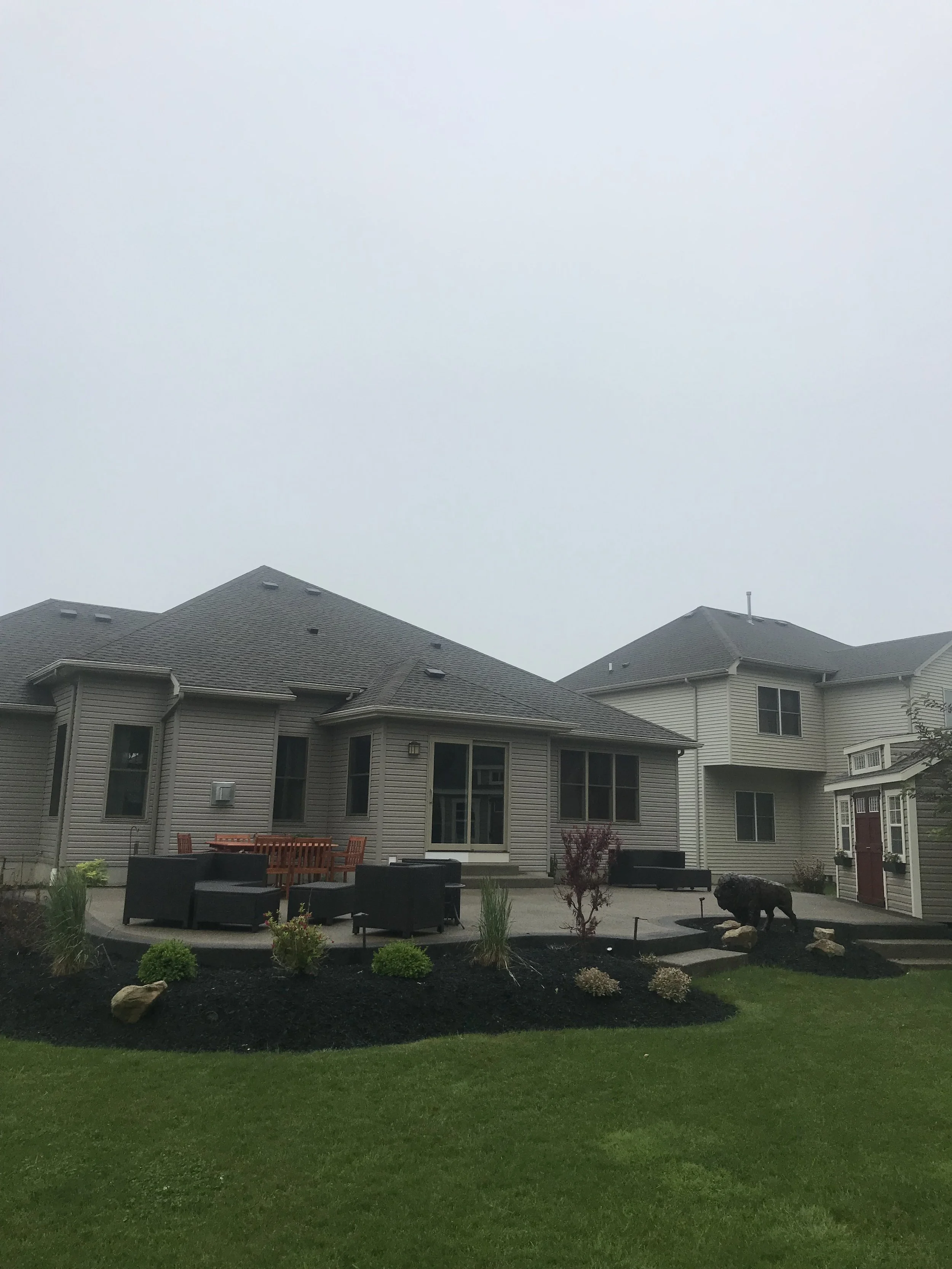 Rochester, NY Backyard Patio. A large house with a curved concrete patio surrounded by gardens.