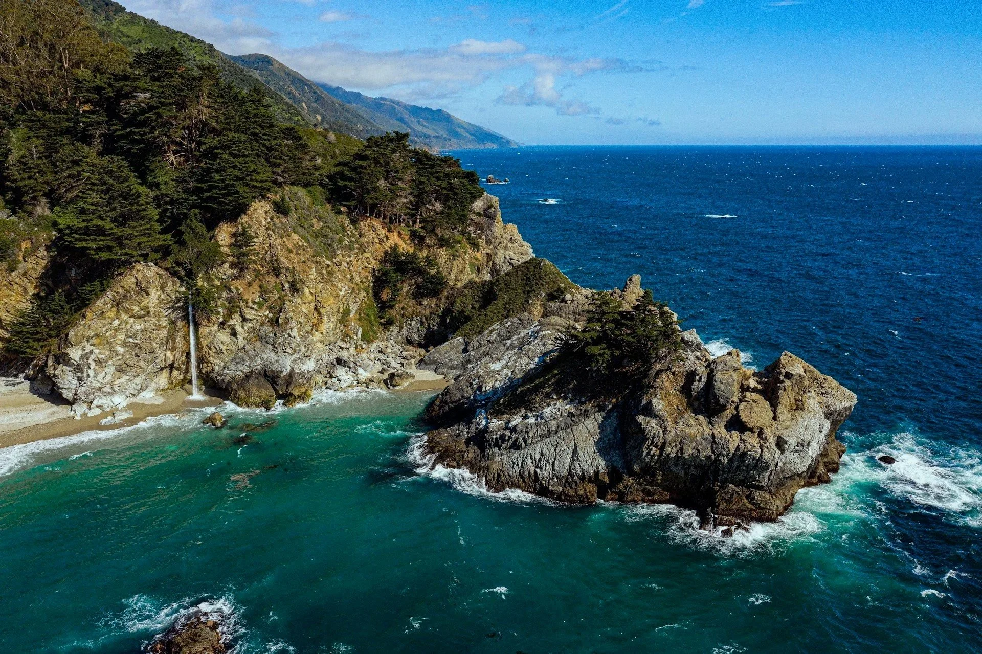 Waterfall flowing onto rocky shoreline along Northern California coast