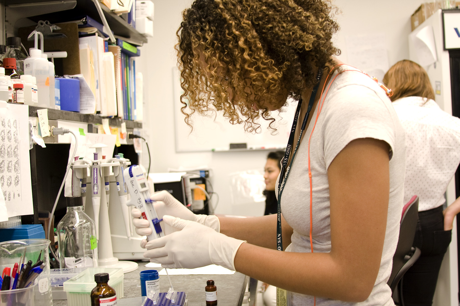 Tabia is genotyping at the bench (the process of determining which genetic variants are present in an animal, in this case, a mouse). The vials contain brain tissue of mouse specimens and she is releasing via pipette the dna out of the tissue.
