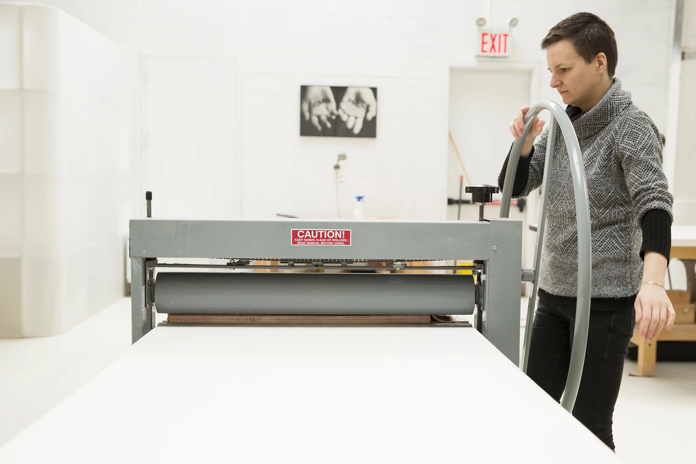  Karolina turns the wheel on a press that flattens a slab of stoneware clay to a certain thickness. 