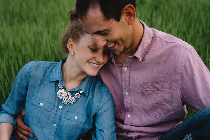 Erin and Scott share a hug while sitting in a field with flowers