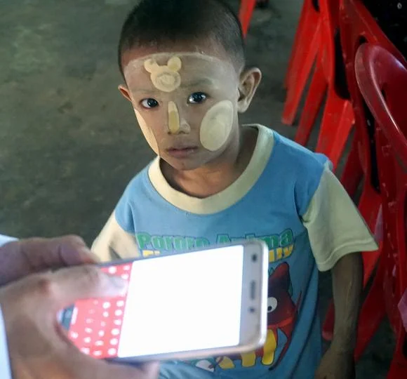 Like children everywhere, this Burmese boy can't get enough of his parents' mobile telephone. (Photo by Denis D. Gray)