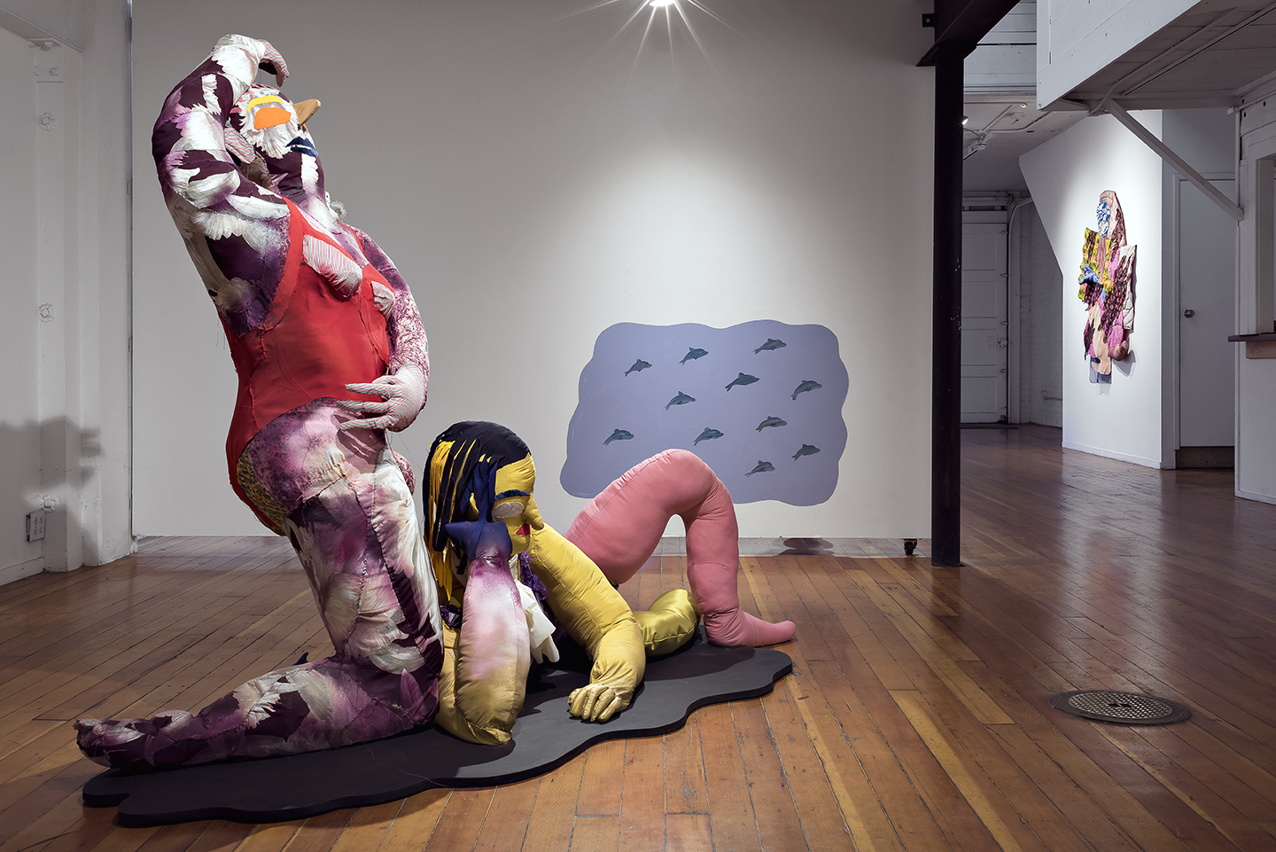 Mujeres (installation view), 2016, fabrics, batting, thread, stuffing, wood, and dolphins figurine, 96 × 65 × 44 inches.