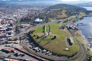 6 Futurist remembrance: An Acconci footbridge for Hobart?: DANIEL THOMAS Aerial view looking northwest along the spine of the Queens Domain. The proposed Acconci bridge seeks to connect the Cenotaph (centre foreground) with the Avenue of Honour (cleared yellow-tinged native grassland in the middle ground); image courtesy Inspiring Place, Hobart. photo: Adam Muyt, Hobart City Council