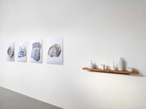 7 Build me a city I Cry me a river: LISA HARMS Kirsten Coehlo, foreground: oil can, cup, funnel, bottle, bowl , 2012, porcelain objects, dimensions variable (tallest 28cm); background: Dreams of Leaving , 2012; four photographs on photographic paper of ceramic shards from new Royal Adelaide Hospital site, North Terrace; SA Museum collection; 80 x 60cm each; image courtesy the artist, Helen Gory Gallery, Melbourne, and BMGArt, Adelaide