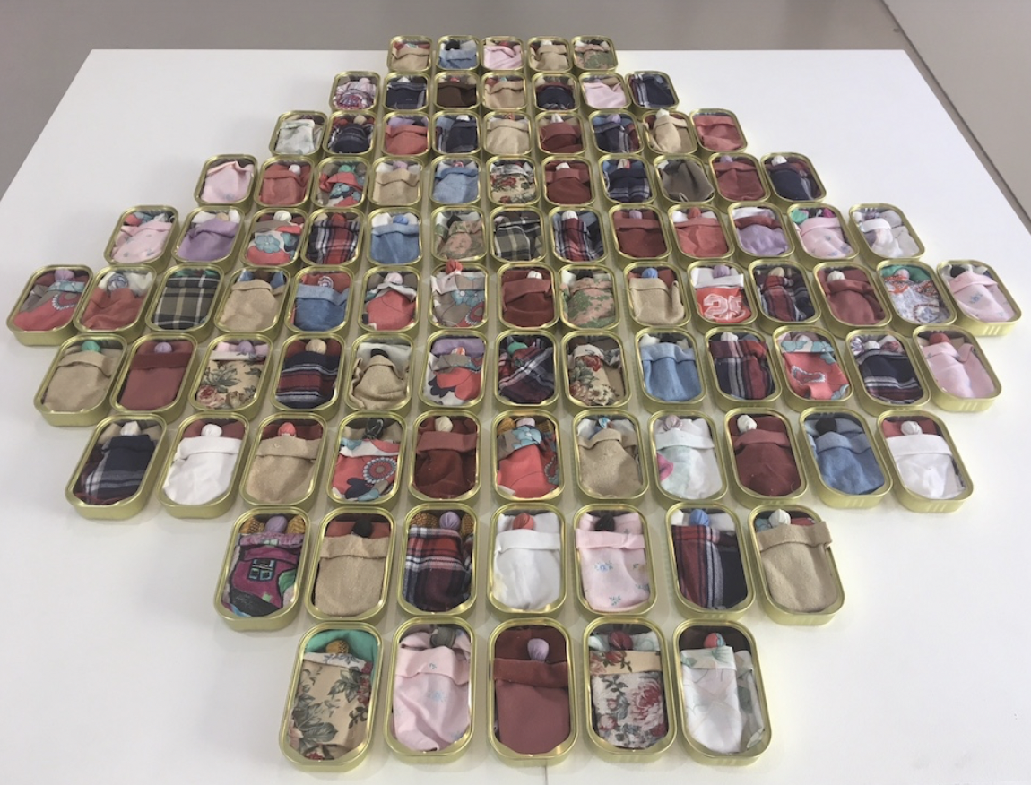  Sharyn Egan,  Our Babies , 2019, 100 sardine tins, cloth, pebble gravel, dimensions variable; courtesy the artist 