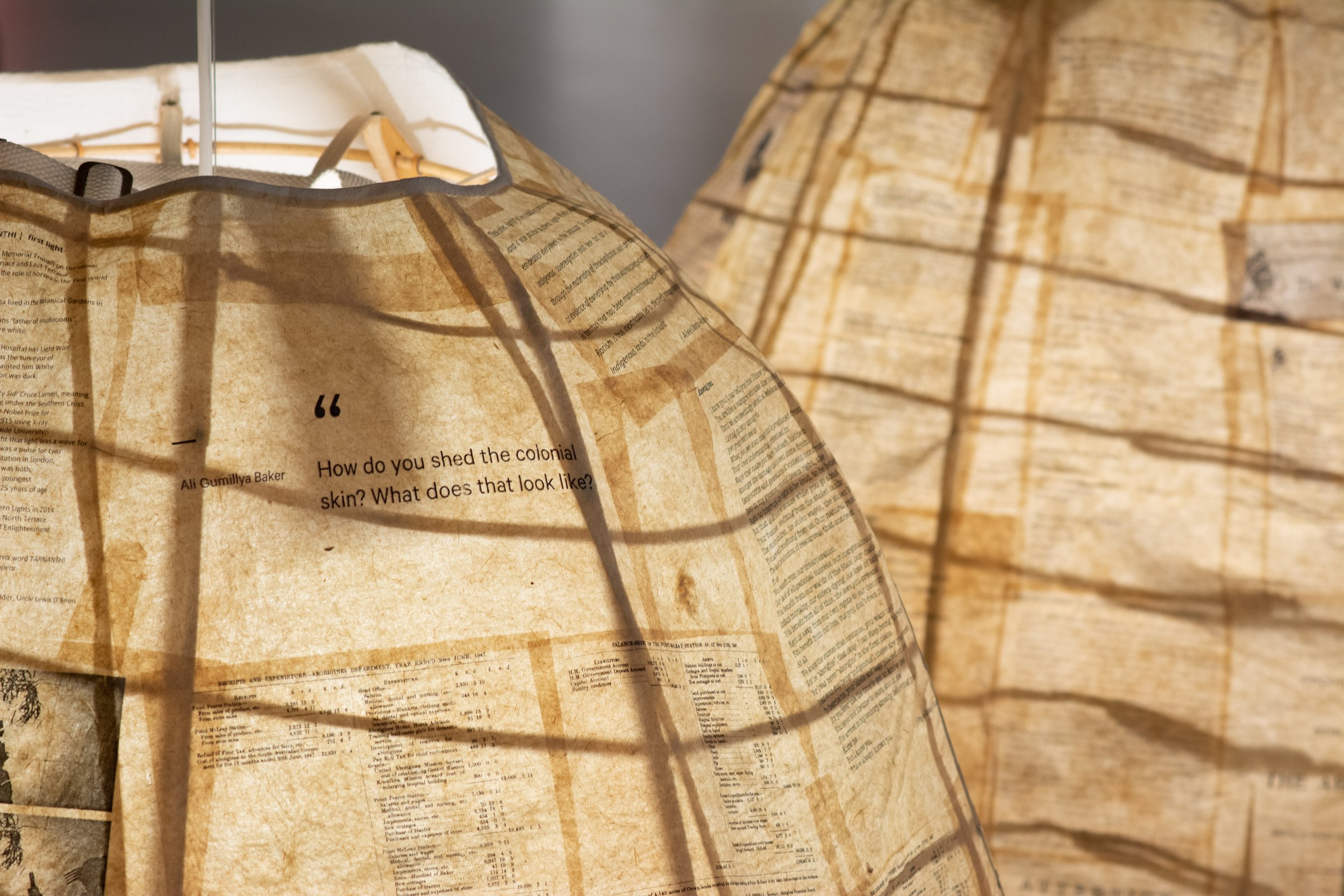 Unbound Collective, Natalie Harkin and Seana O’Brien, Archive Performance Skirts (detail), 2019, calico, poems and archival material on banana leaf paper, marine ply and bamboo, foliage, incandescent bulb with wiring, variable sizes.