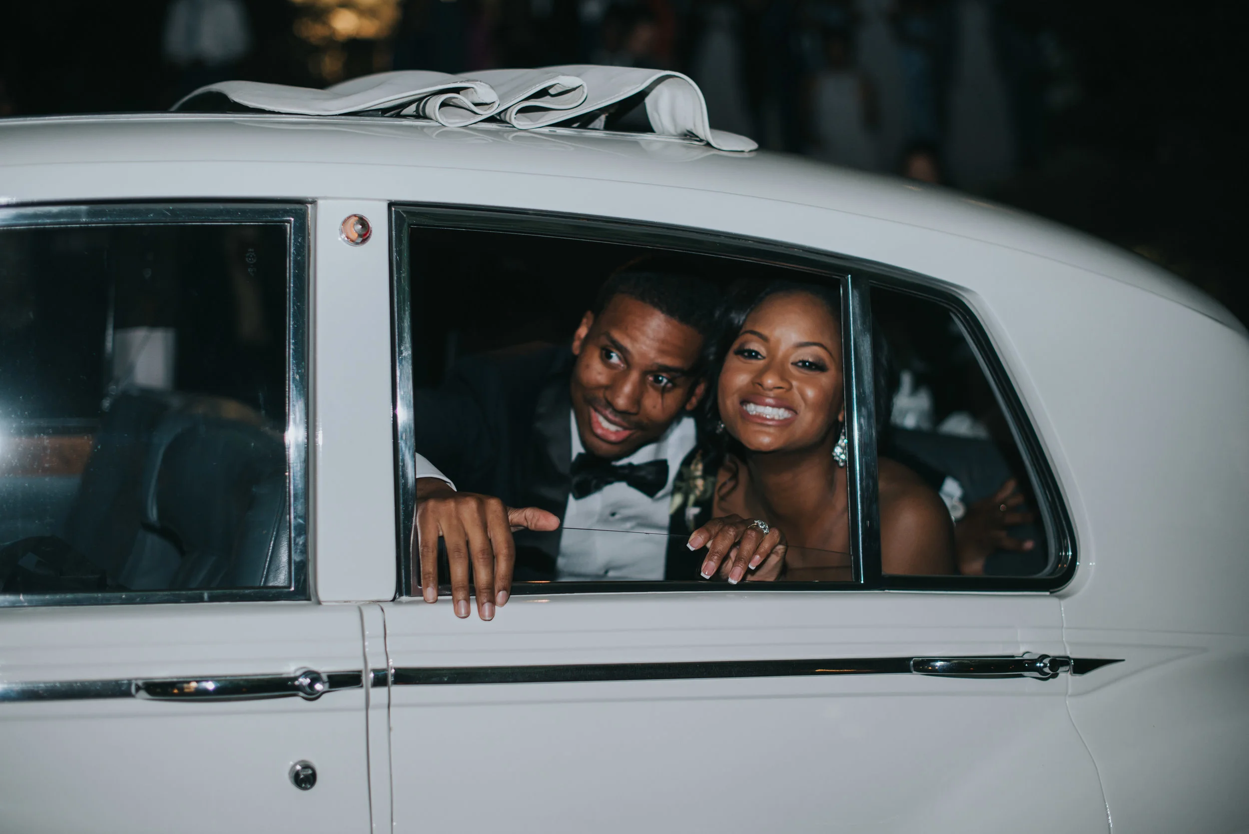 Bride and groom smiling in vintage car