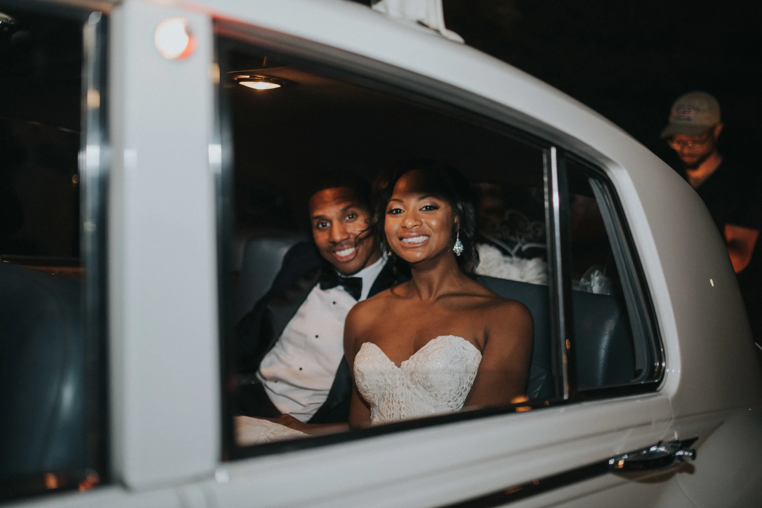 Bride and groom smiling in vintage car