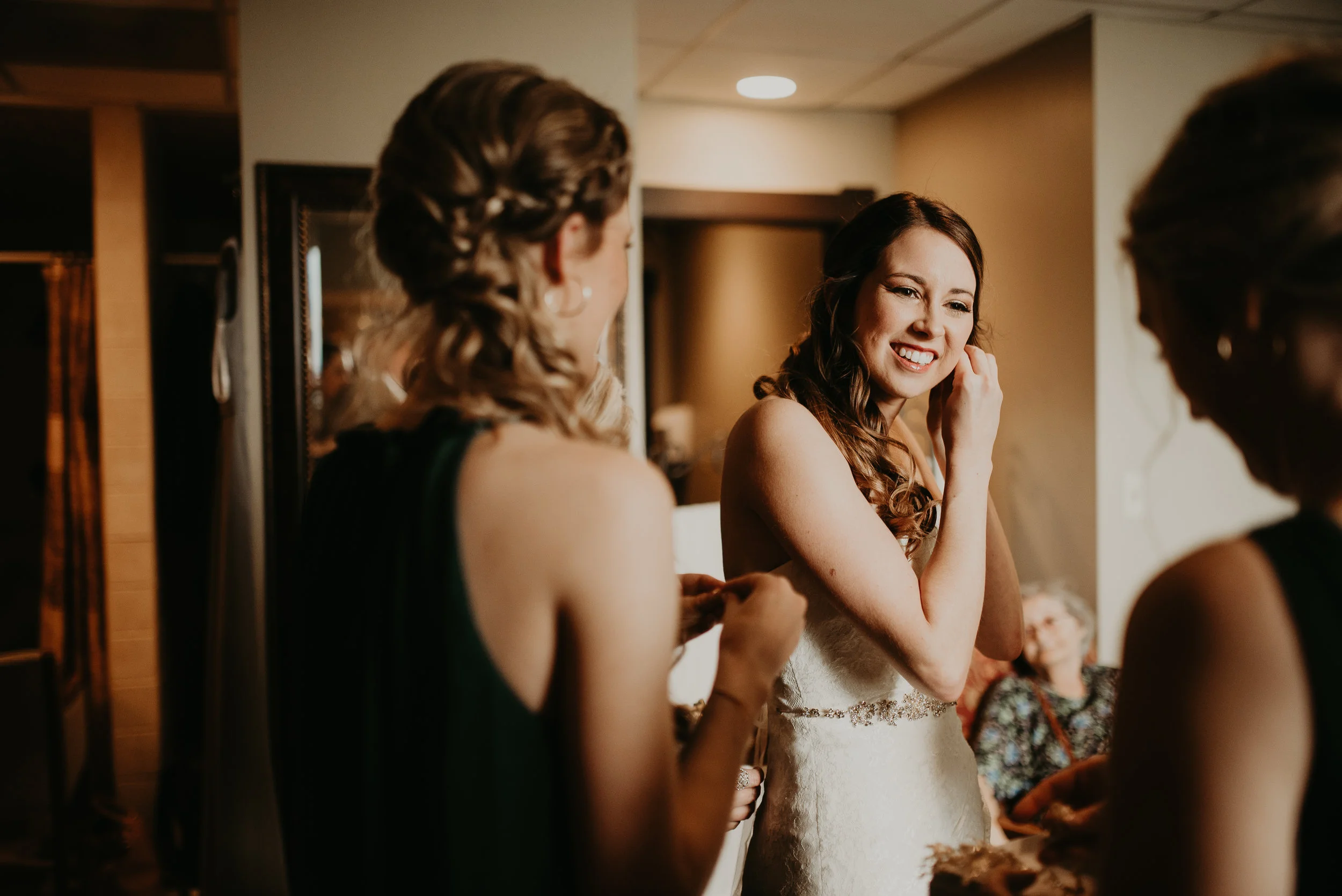 Bride smiling while putting diamond earrings on