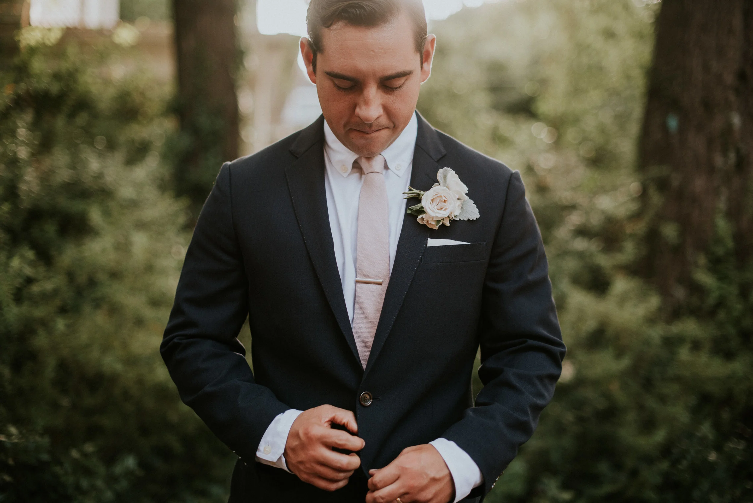 Portrait of groom buttoning navy suit jacket