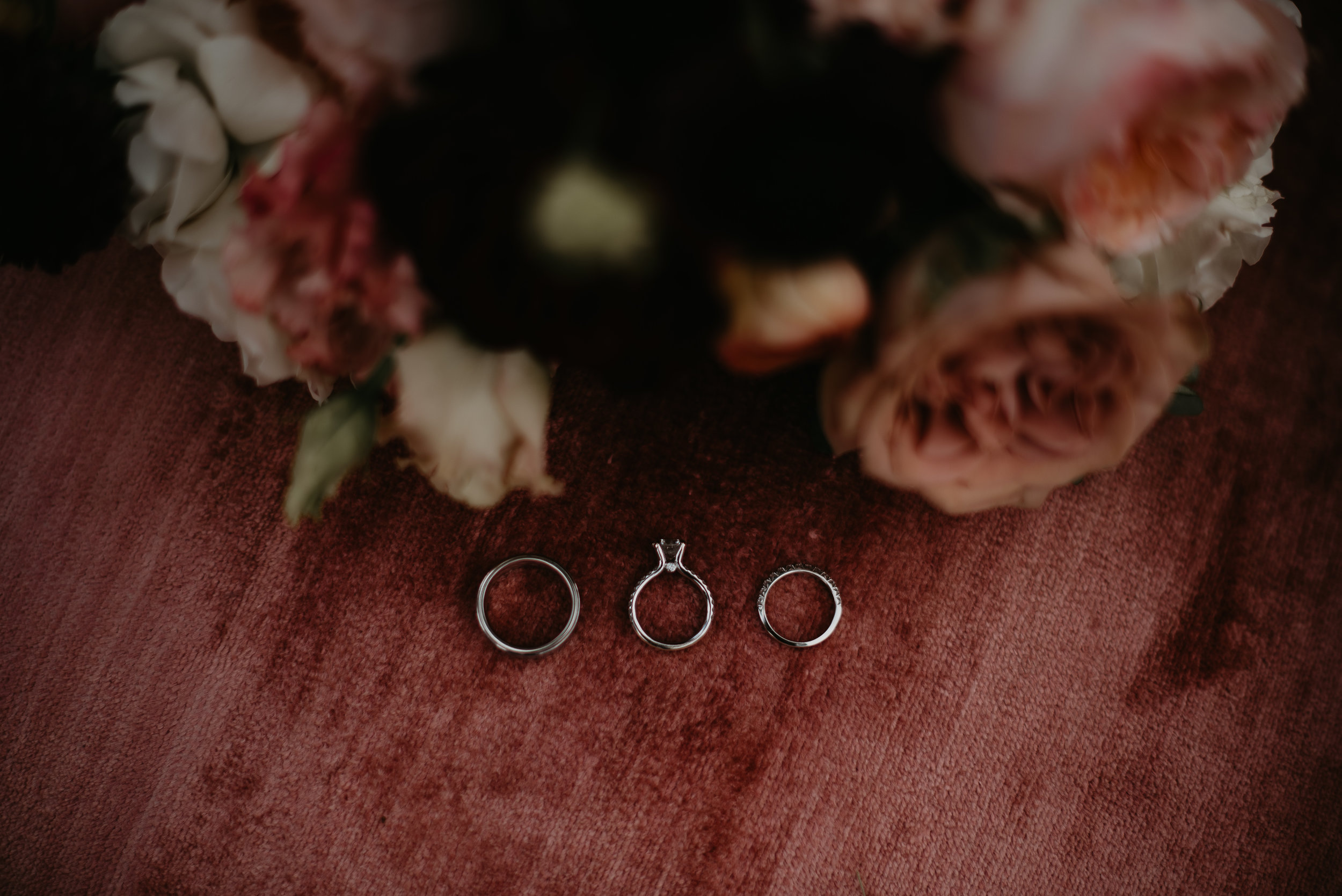Wedding rings with bouquet on red velvet