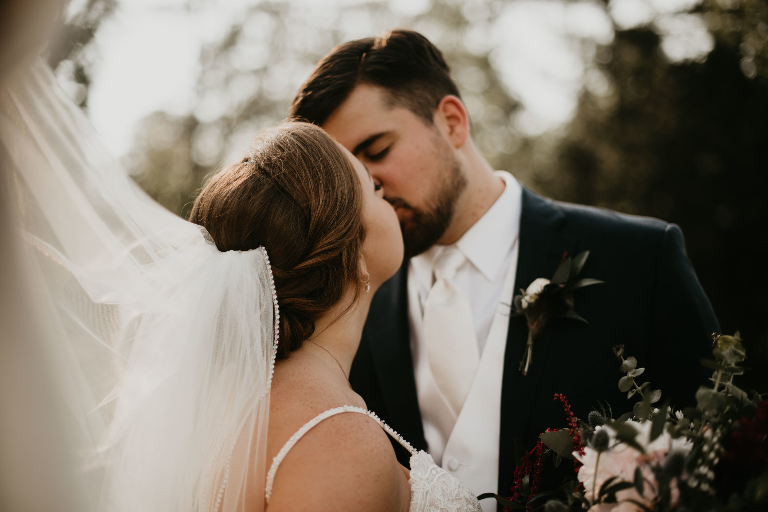 Newlyweds kissing with wind-blown veil