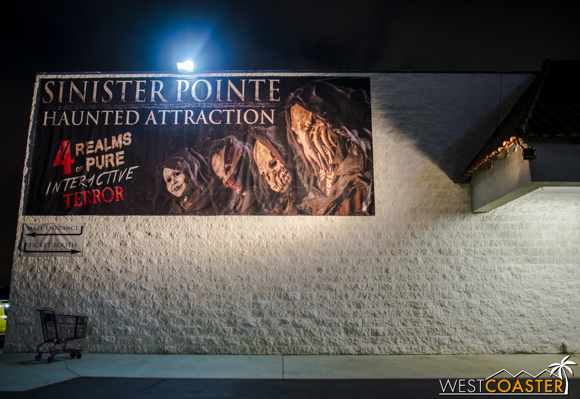 A banner at the front of the big box store building directs guests to the back, where the entrance is.