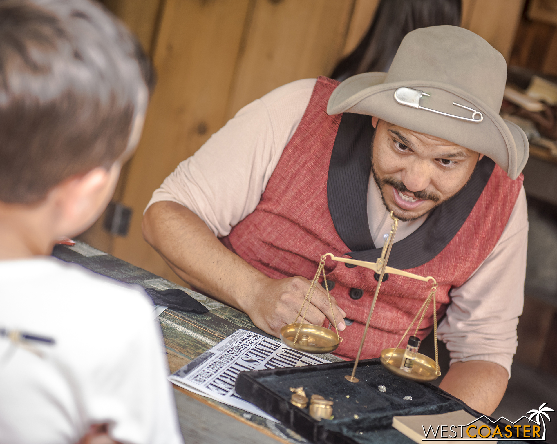  “Peg Leg” Cinch ascertains the value of gold that a young guest has brought to be assayed. 
