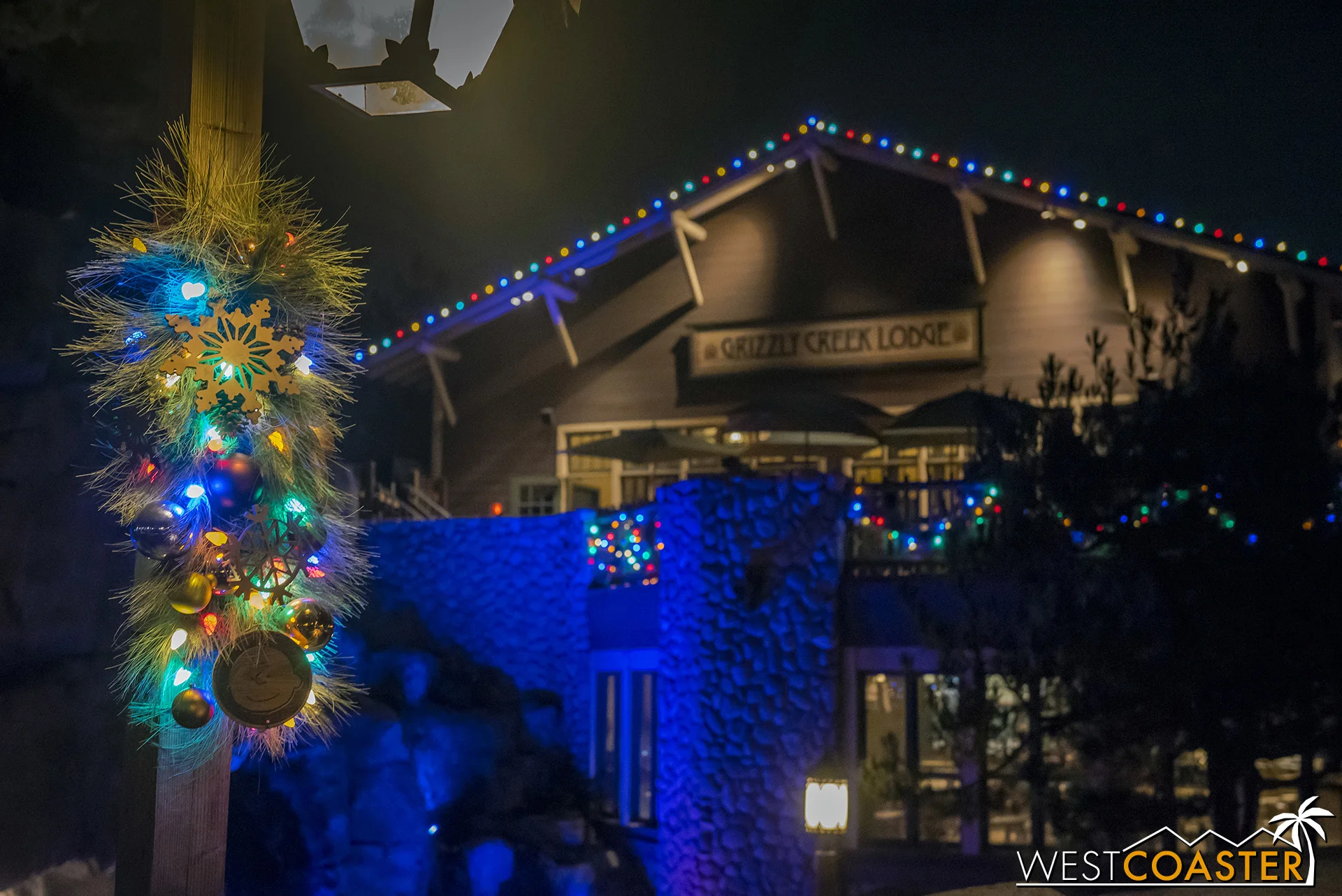 Christmas wreaths line lampposts along this woodsy area.