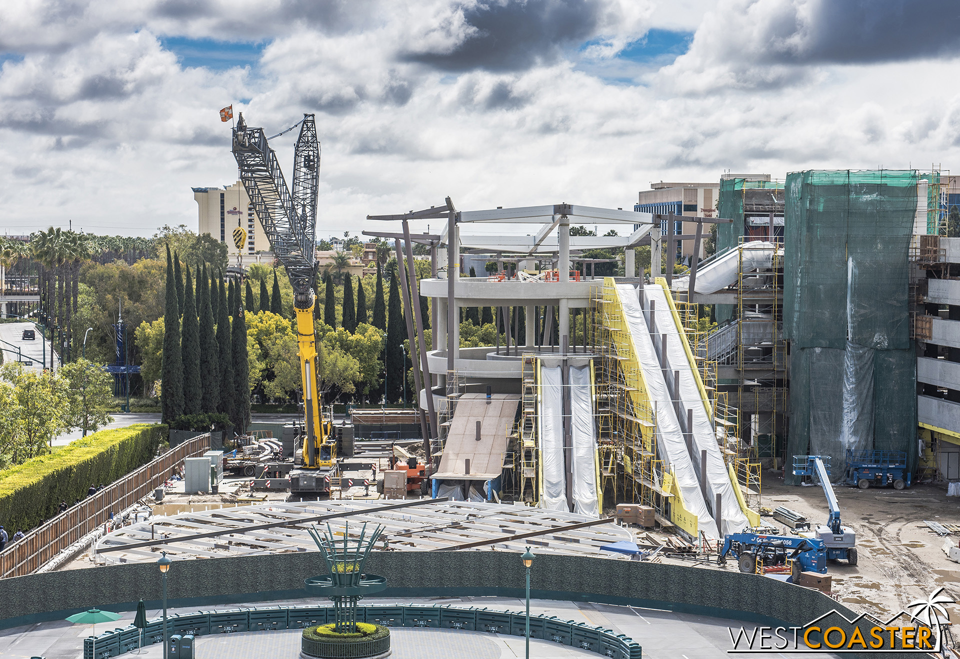  The giant, circular canopy still remains on the ground, but they’ve thrown up some steel beams and columns up the sides and top of the escalator promenade to support it. 
