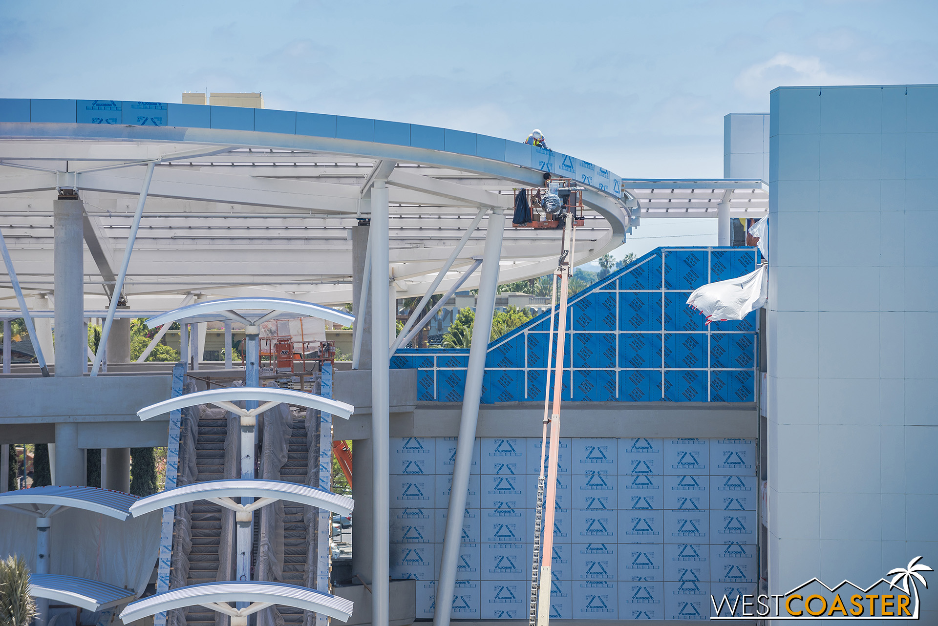  Workers continue to install the aluminum composite panel fascia at the canopy. 