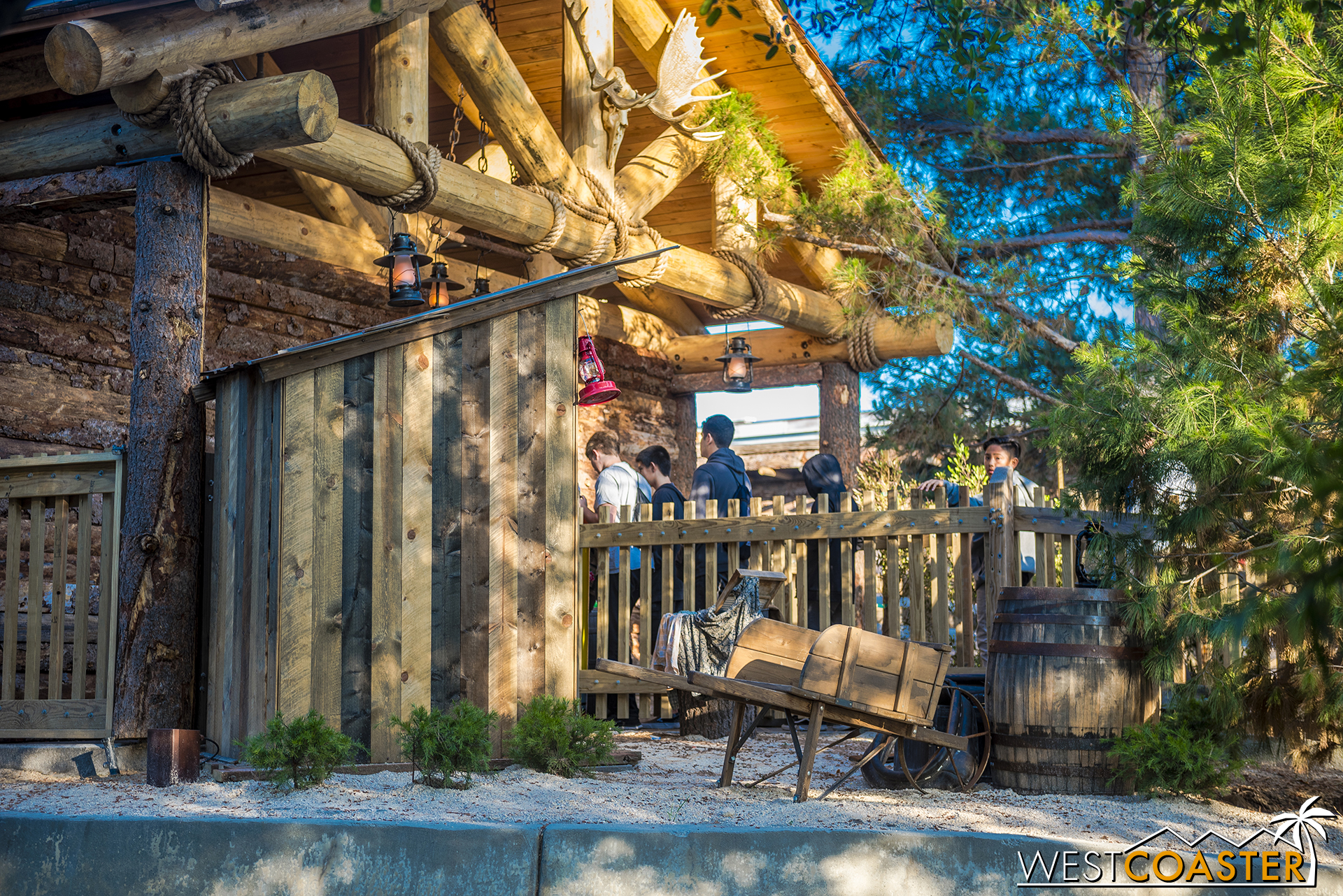  Guests pass by signs of the outpost, like a cart and an outhouse. 