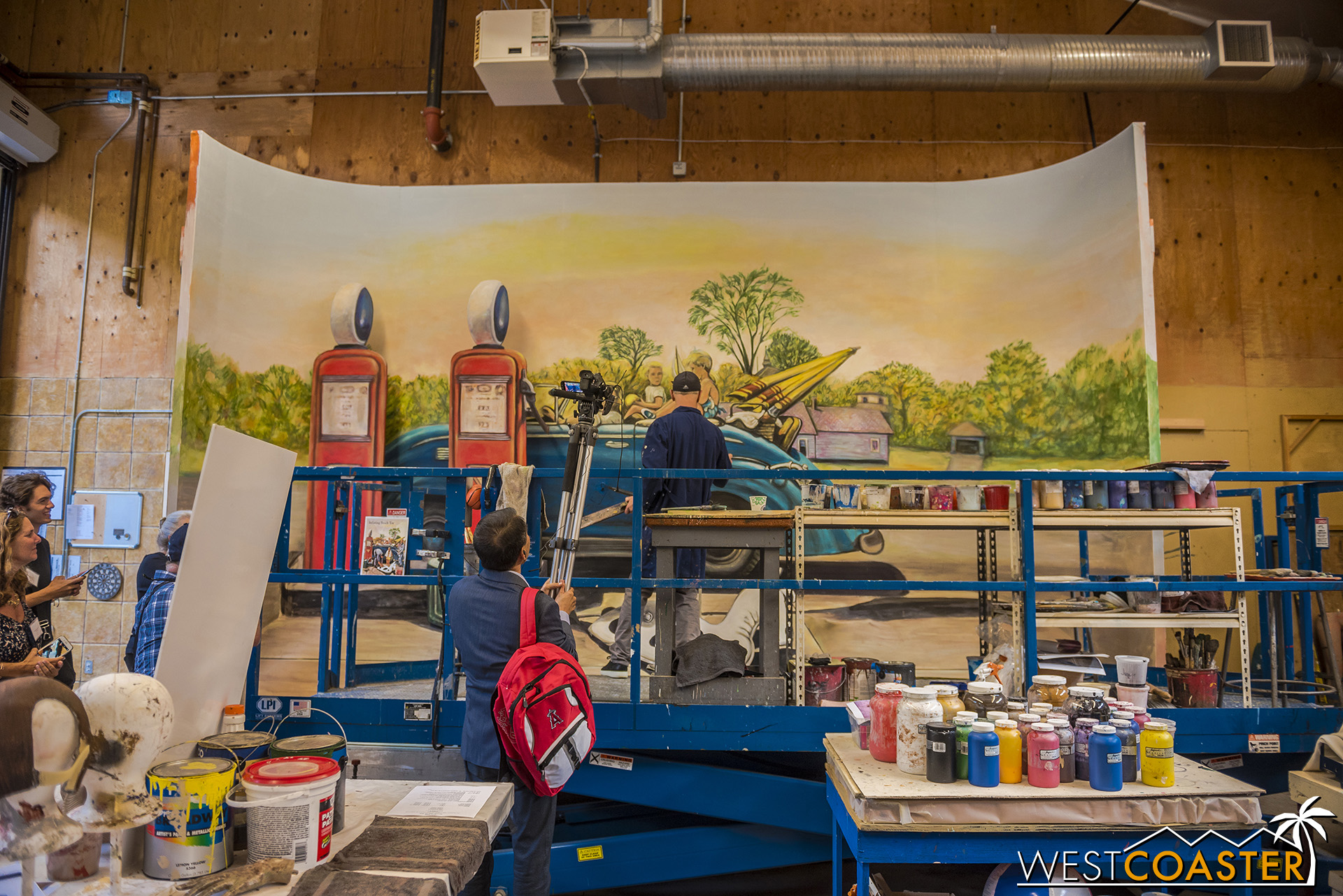  Inside a warehouse, an artist works on a backdrop to one of the paintings that will be recreated. 