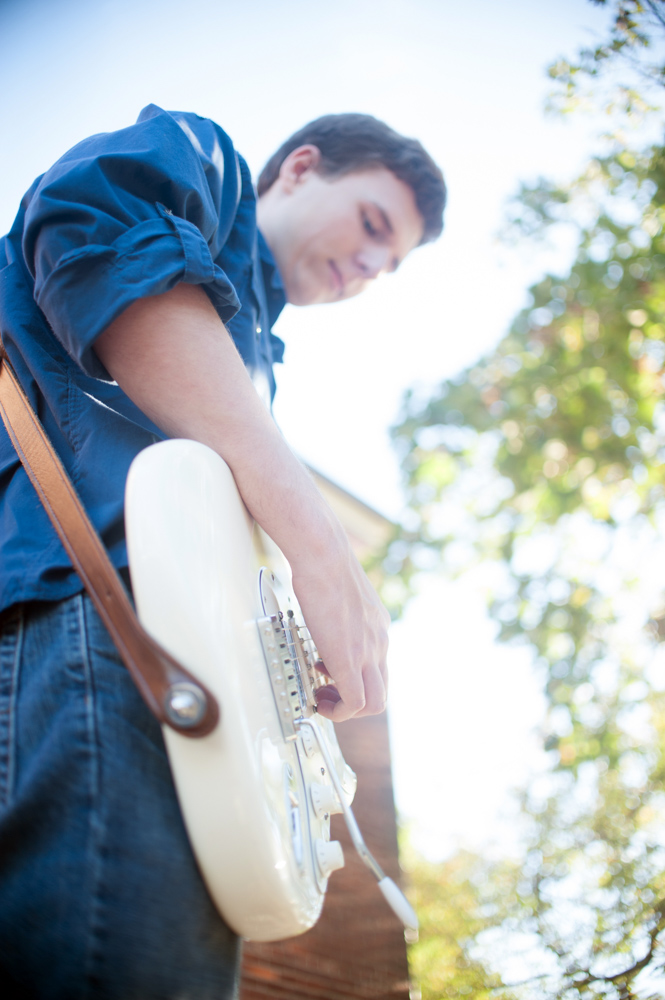 Handsome Young man playing guitar during senior portrait session