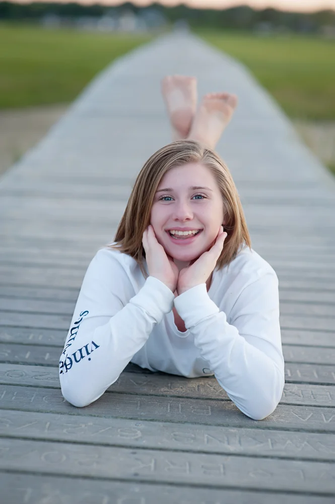 Young tween laying on boardwalk in Sandwich MA at Sunset