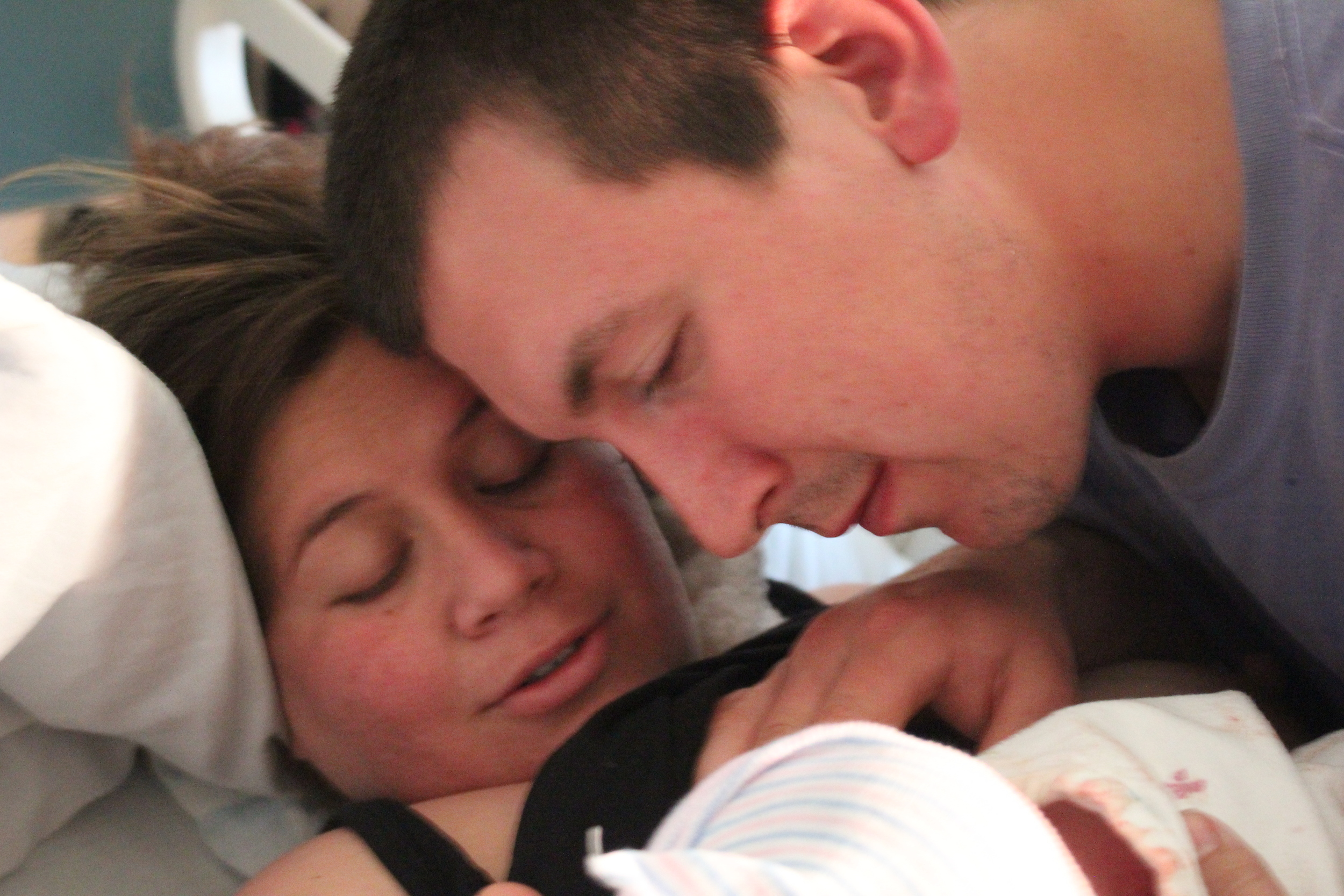 Baby is here! Dad and mom bonding. Doula keeping her distance. Dad and mom rocked an all natural, gentle birth and did it with grace. She couldn't have done it without dad and a their birth team: nurses, doctor & doula, all working together to support them both.