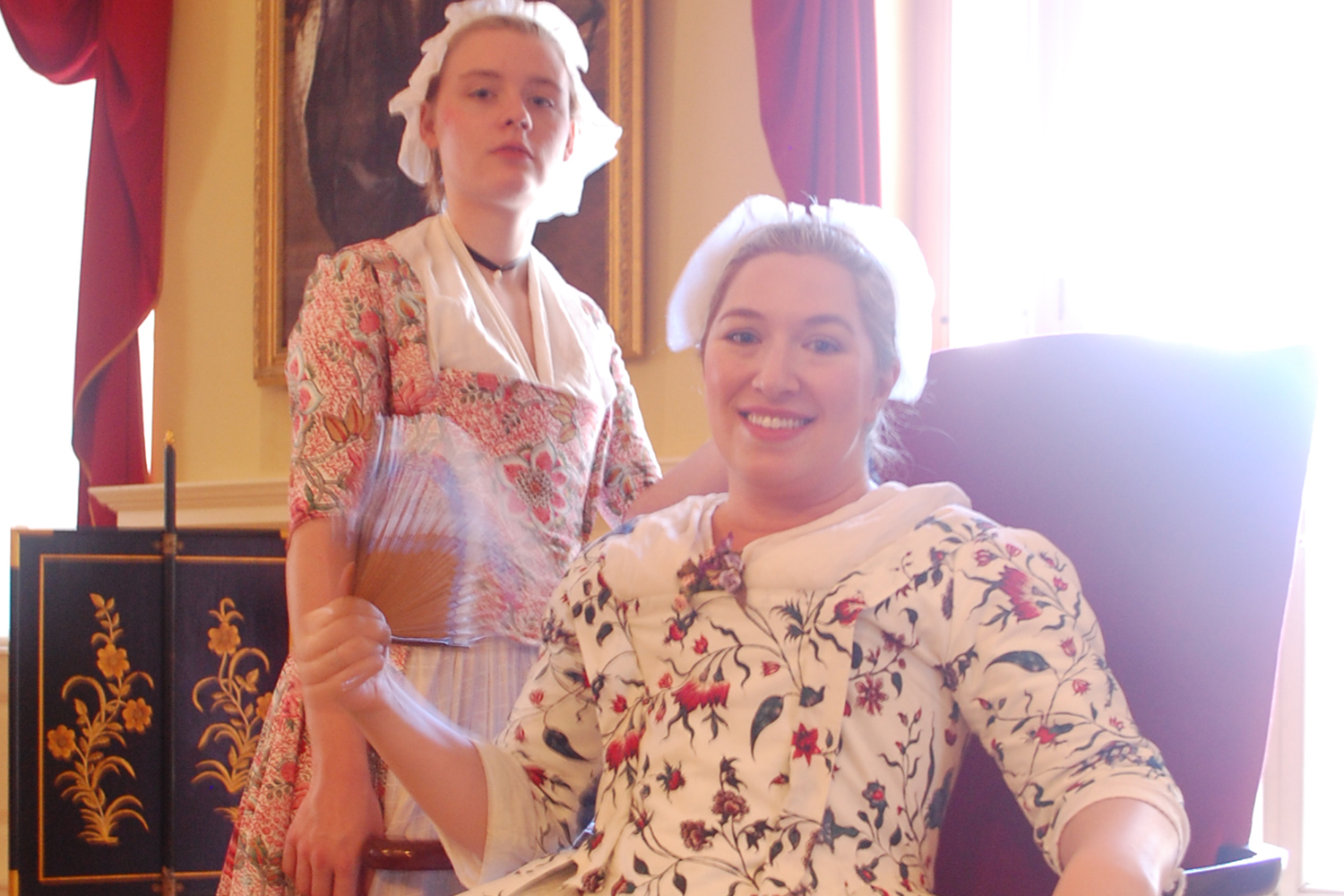 Two young women in 18th century costume in the Council Chamber of the Old State House.