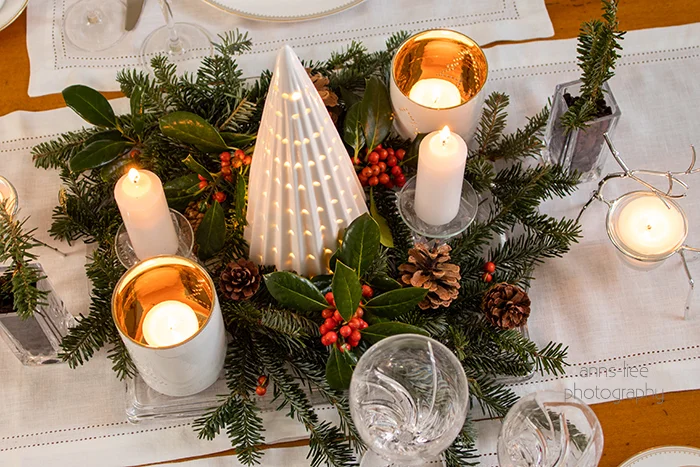 Christmas centerpiece with ceramic Christmas tree, hollies and berries, Frazer fir stems and candles.