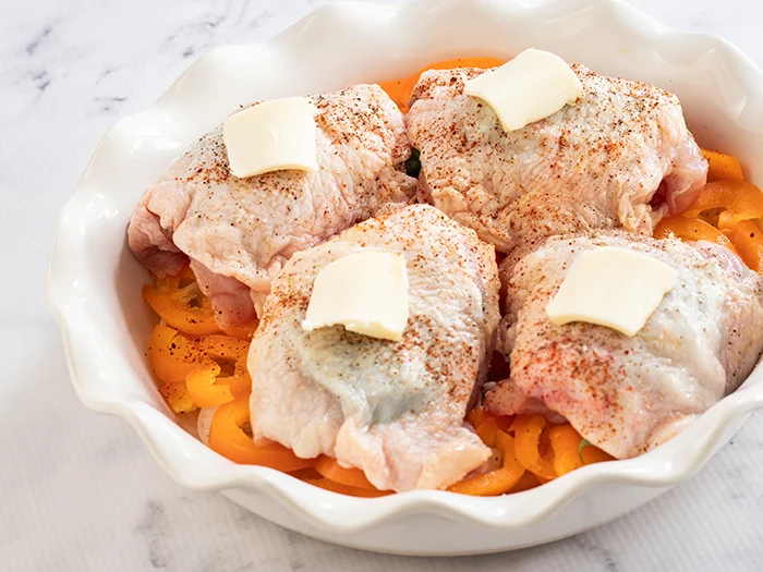 Raw chicken thighs stuffed with tarragon in casserole dish