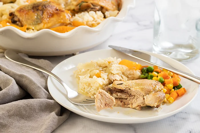 Close up of baked tarragon chicken thighs with rice on a plate