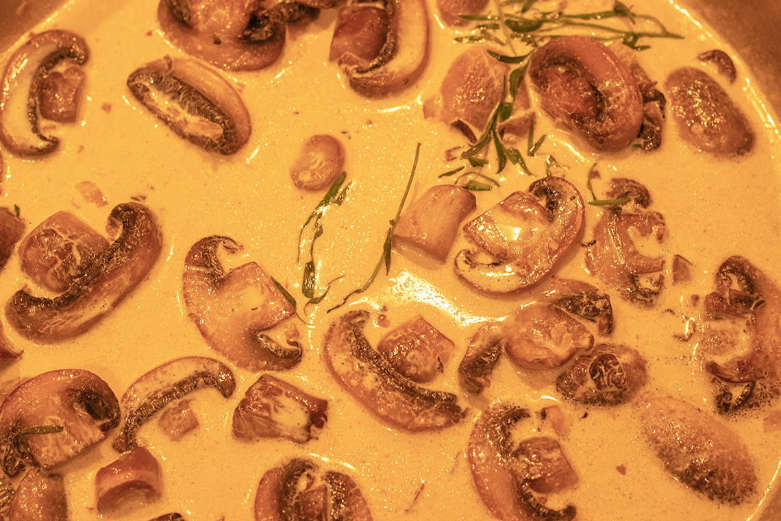 Creamy sauce with mushrooms and tarragon sprigs.