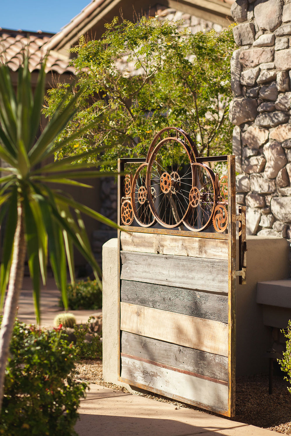 A unique fence made from vintage bike rims makes a statement on the exterior of the home. Image: James Stewart