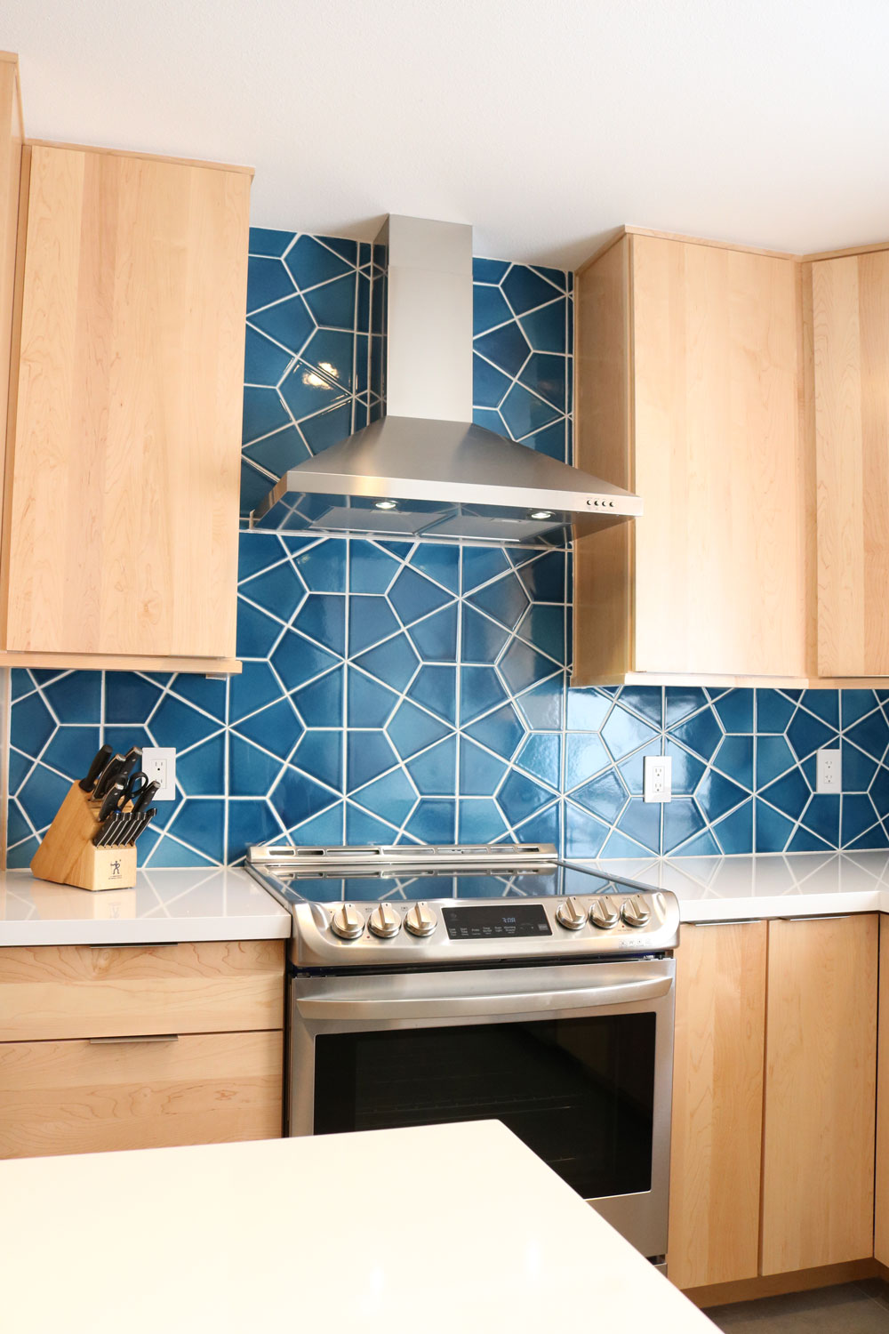 We balanced cool and warm tones with a bold kitchen backsplash from Fireclay, and natural wood cabinets to add dimension and a pop of interest in this kitchen design. Image: Monica Milewski