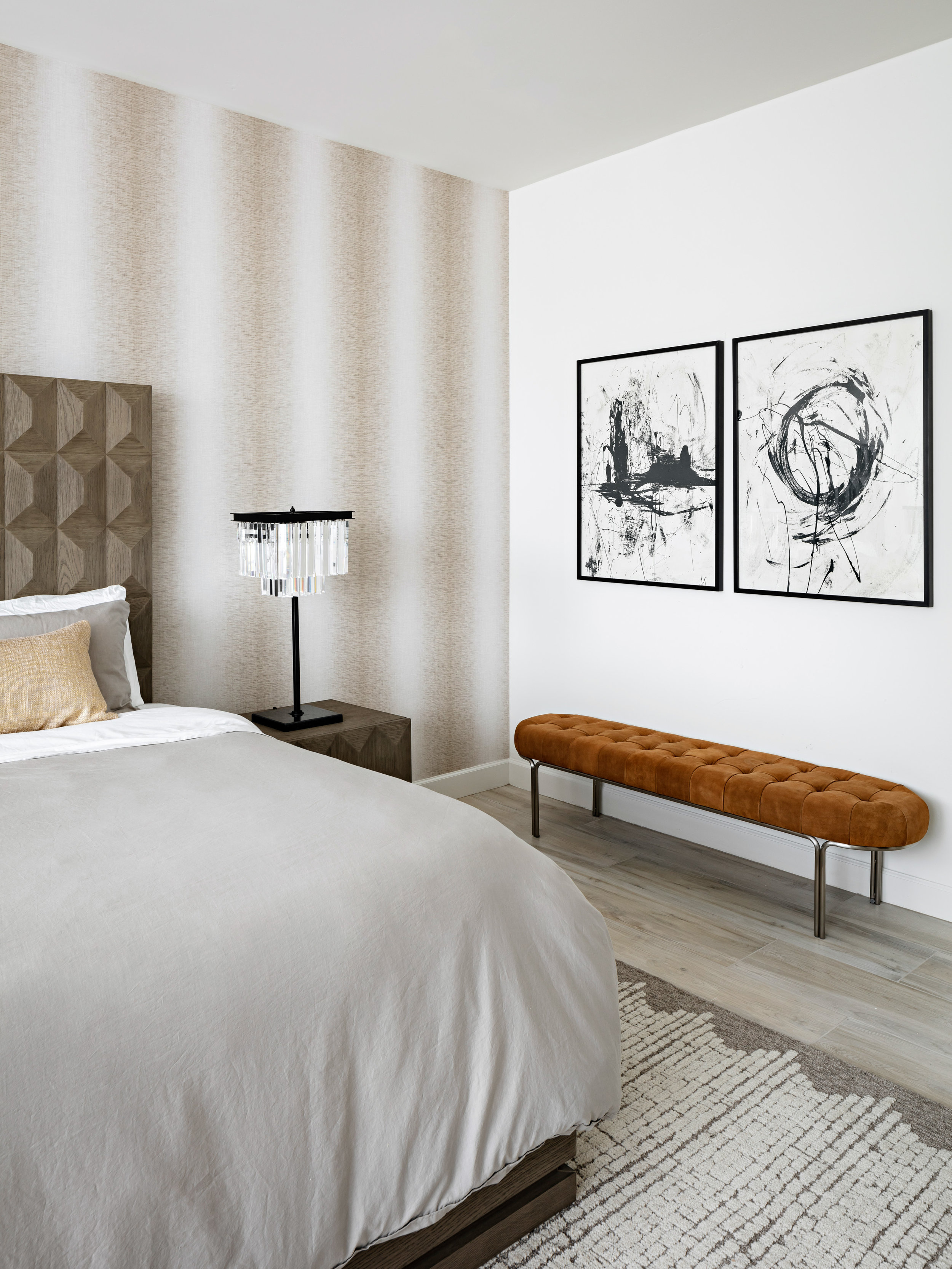 We elevated this master bedroom with an ombre wallpaper, adding depth to the neutral palette of this bedroom. A tufted bench brings in a pop of color underneath the abstract paintings on the wall. Image: Roehner + Ryan