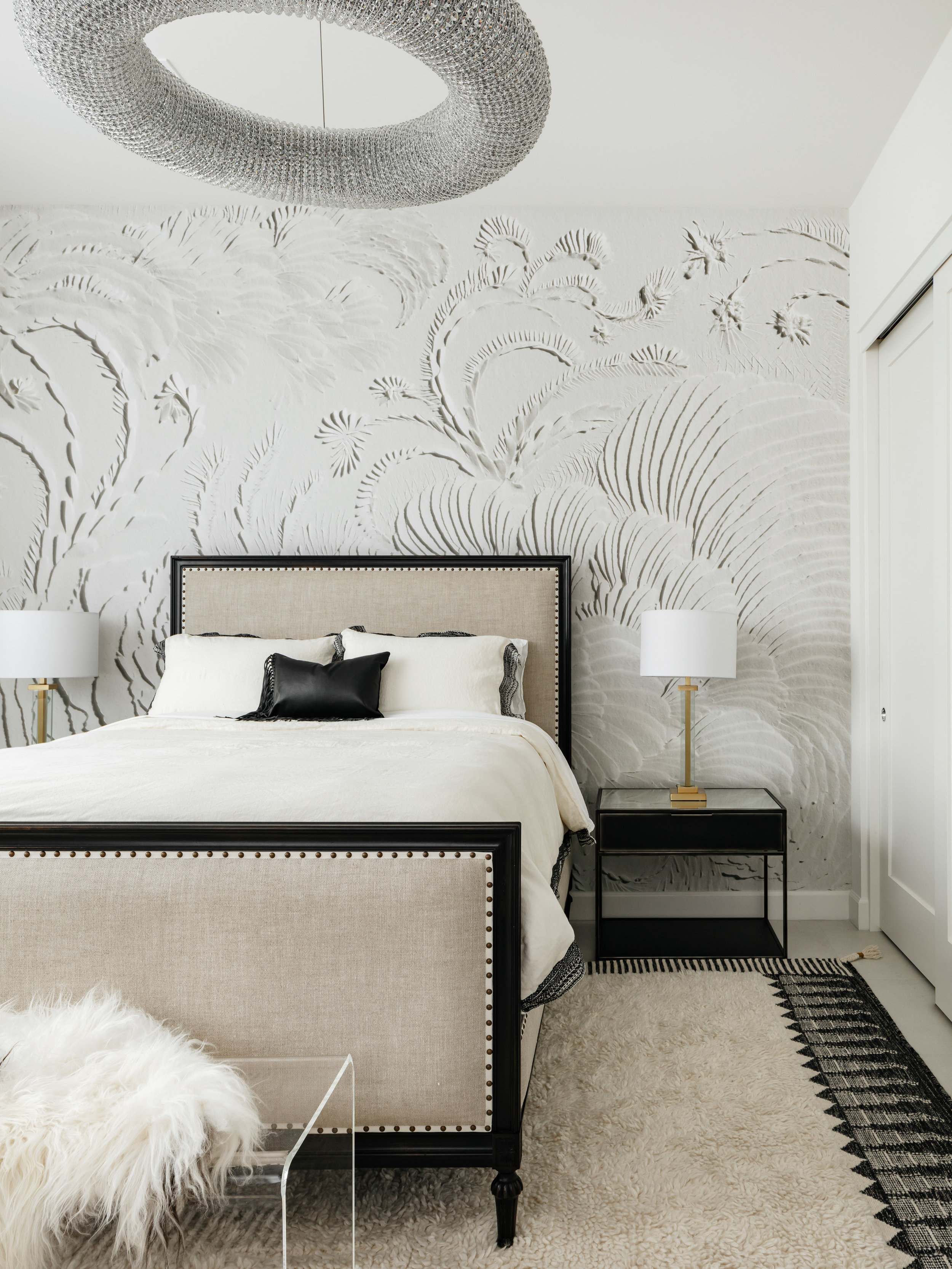 Elegant baroque textured wallpaper adds dimension to this bedroom design. Just the right amount of contrast between accents and the rug allow for the space to remain open and airy, yet absolutely inviting. Image: Roehner + Ryan