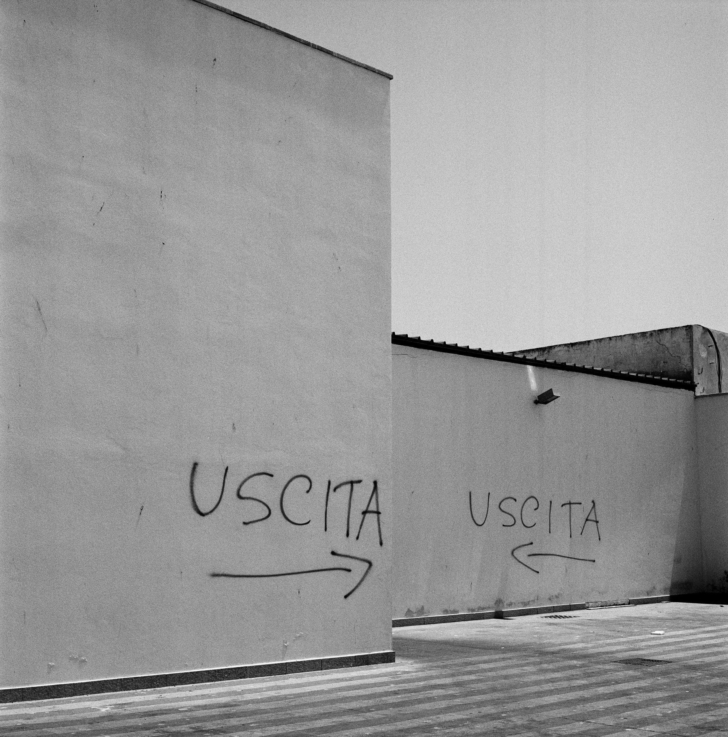  Two converging signs indicate "Exit" on the walls on the fish market in Trapani on the west coast of Sicily. July 2015 