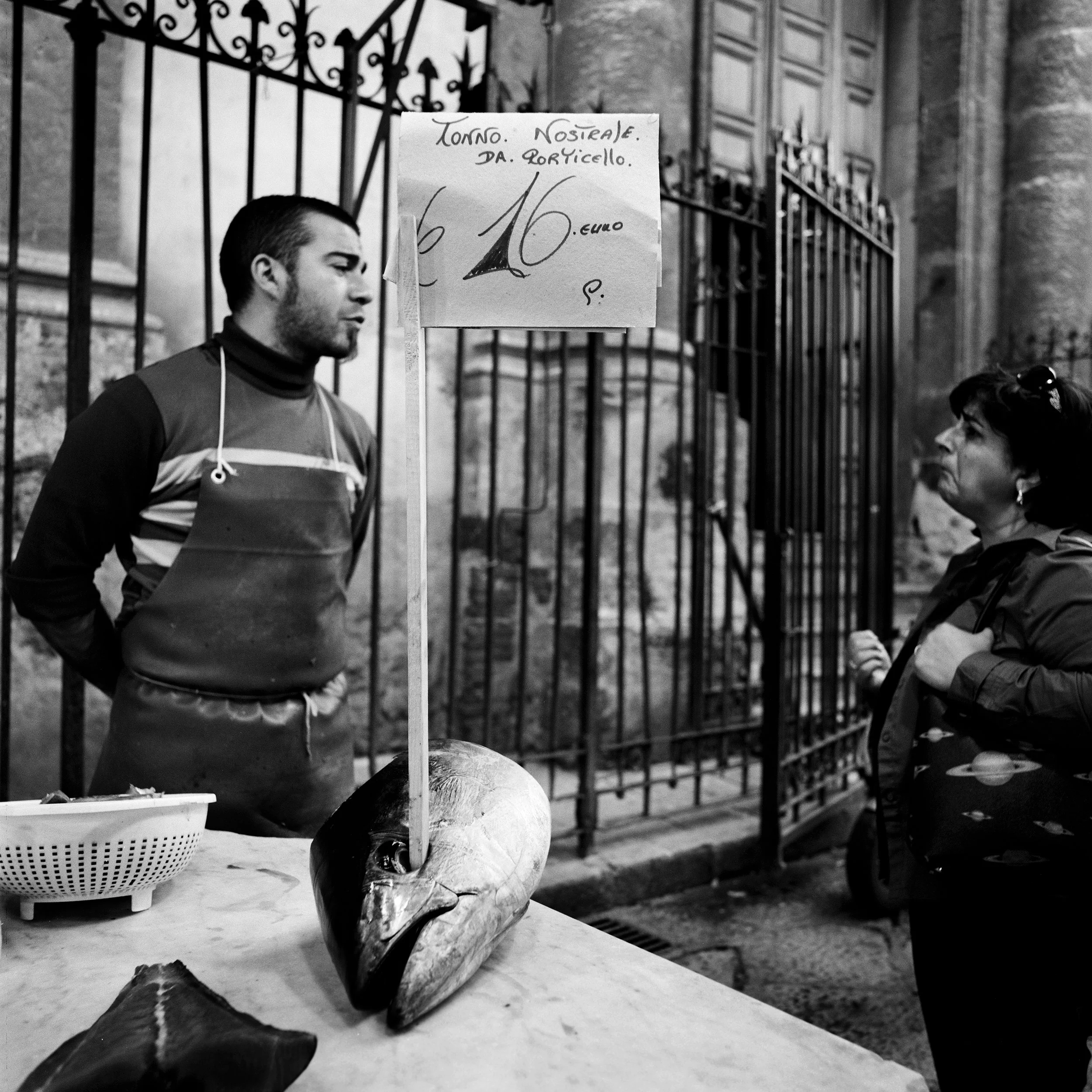  A fishmonger chats with a client at the historical street market of Capo in Palermo. 