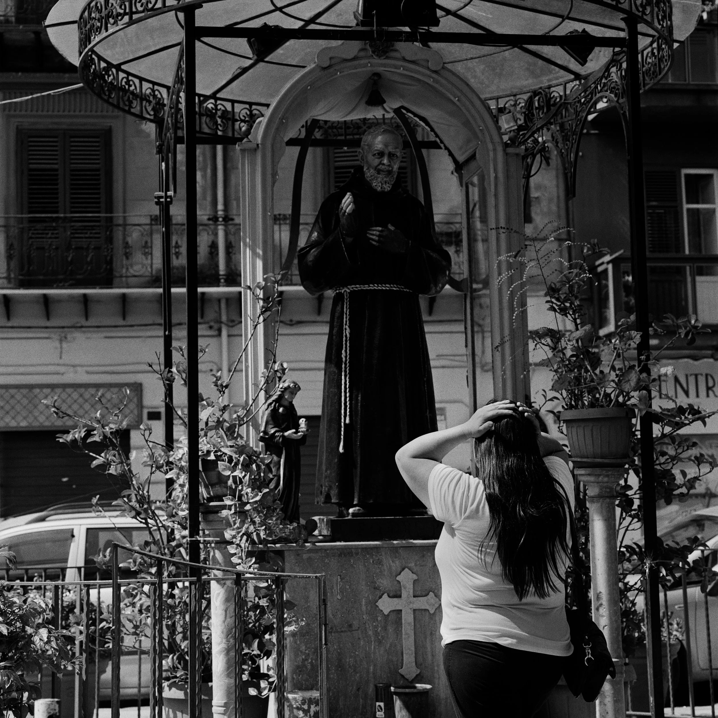  A woman appears in distress while praying in front of the statue of Saint Padre Pio near the Central Train Station in Palermo. 
