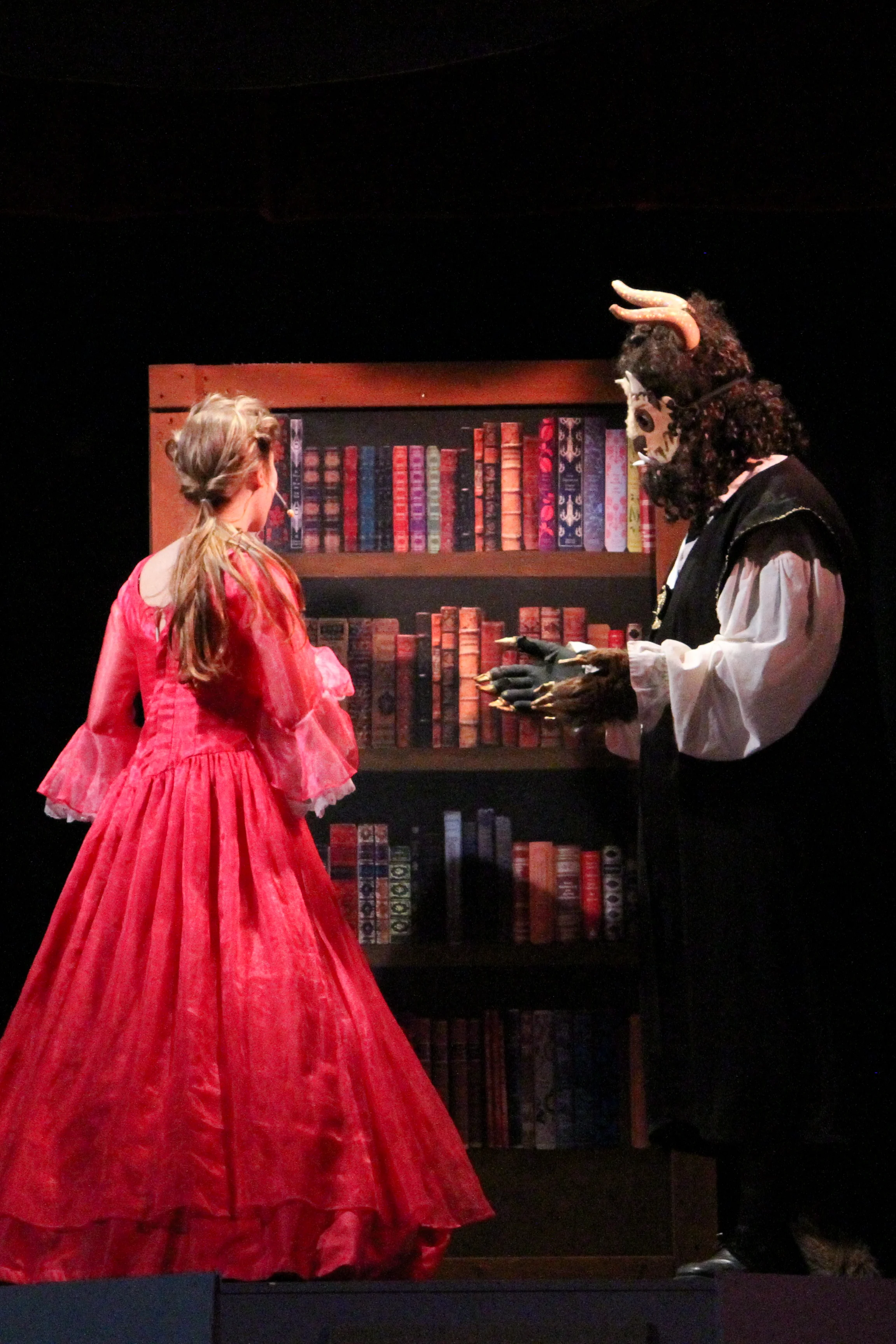 After sharing a romantic evening dance together Beast ( Remington Slater, junior ) shows Belle ( Emily Powell, senior ) his extensive library.
