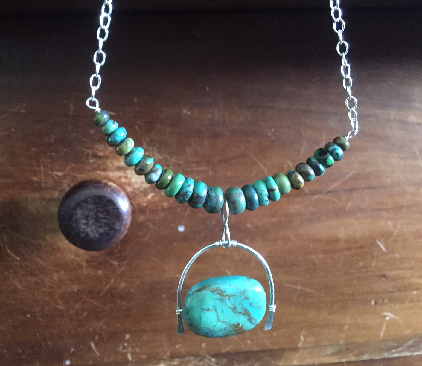 Turquoise Drop wrapped with Sterling Silver Horseshoe design. Dangles from graduated turquoise beads and sterling link chain.