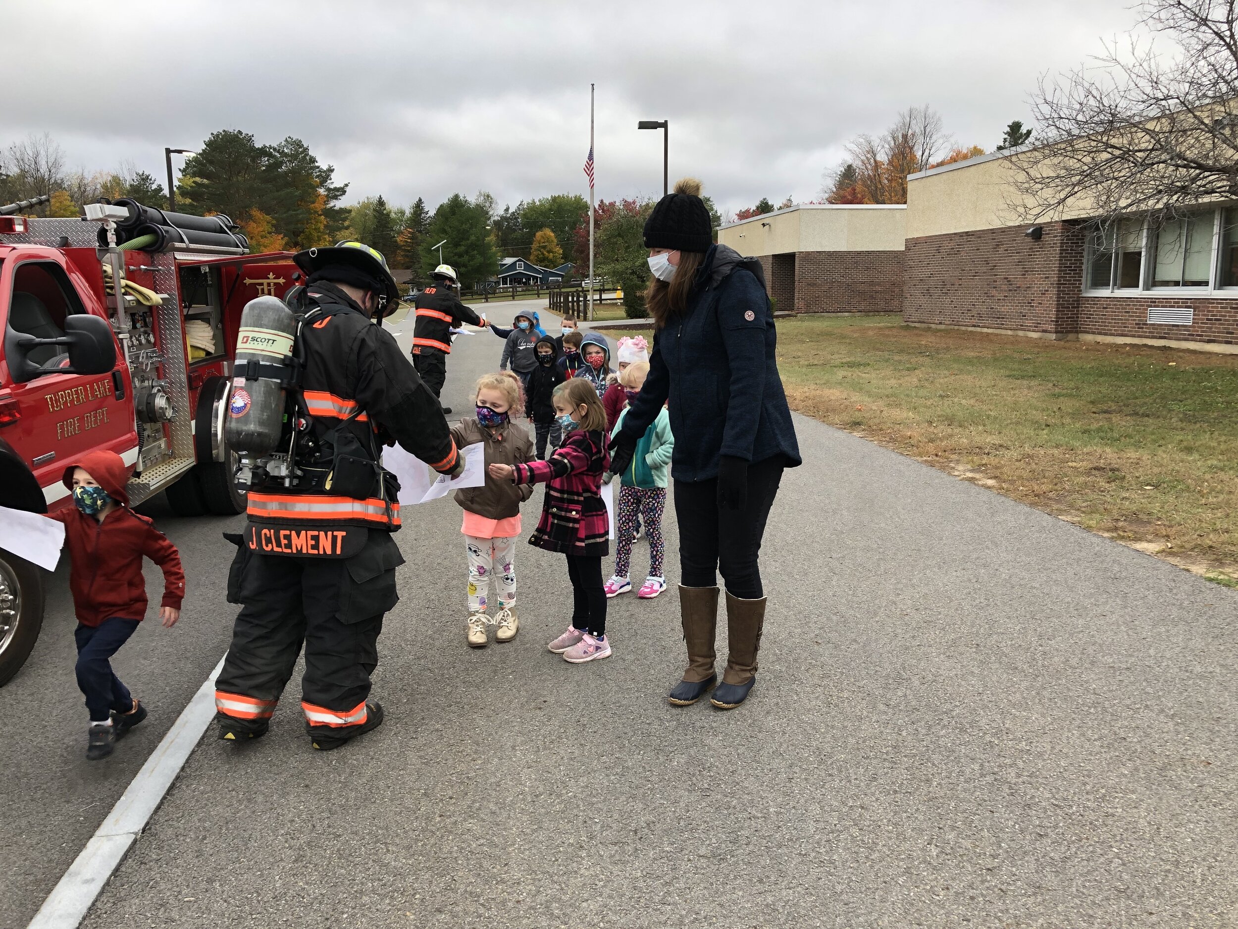   Children in Mrs. Safford's kindergarten class hand out drawings about Fire Prevention Week they made for the visiting firemen Thursday.  