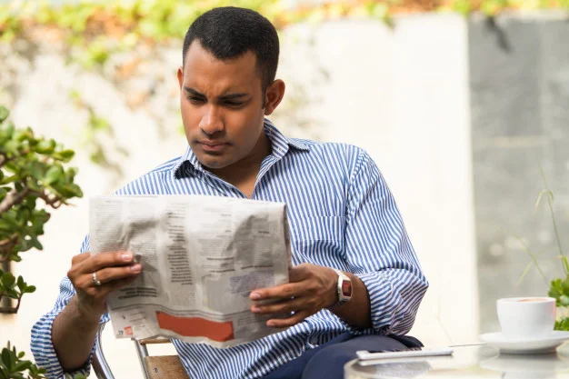 serious-man-reading-newspaper-in-outdoor-cafe_1262-6209.jpg