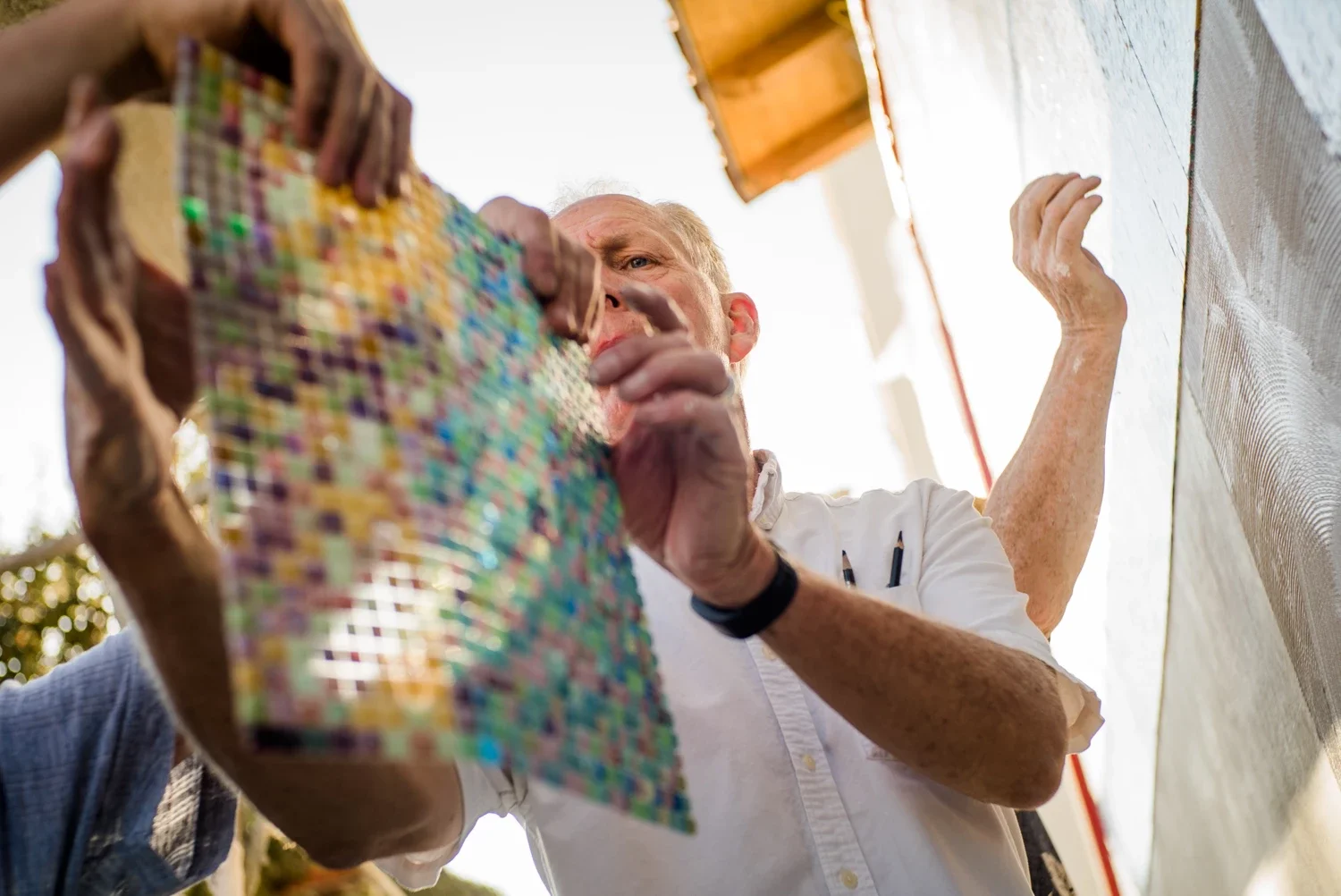 Artist Kenton Nelson grabbing a tile of mosaic glass during installation of the Pasadena Playhouse Mosaic Mural by Erwin Darmali