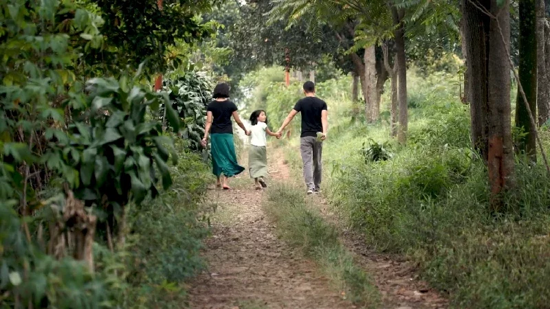 Man with his wife and youngest daughter walking calmly in a walking path in the midst of trees and vegetation