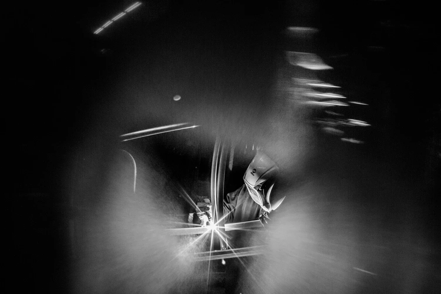 A welder in a welding gear is captured through the cutout of the welding curtain