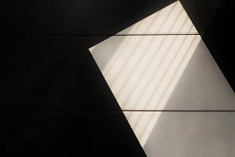 Abstract geometric composition with diagonal light and dark shapes on tiles.