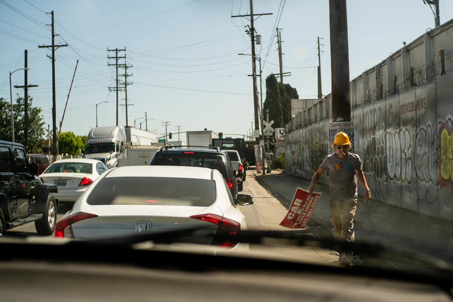 Man carrying a sign on the side of the road as traffic is stopped