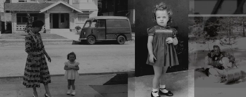 Black and white photo of three children and an adult woman outside in a residential neighborhood. The woman is standing with two young girls, one in the street and one on a sidewalk. The street has a vintage van parked, and a house with a porch is in the background. The girls are dressed in dresses, and there is a child sitting on the snow with a toy in the right part of the image.