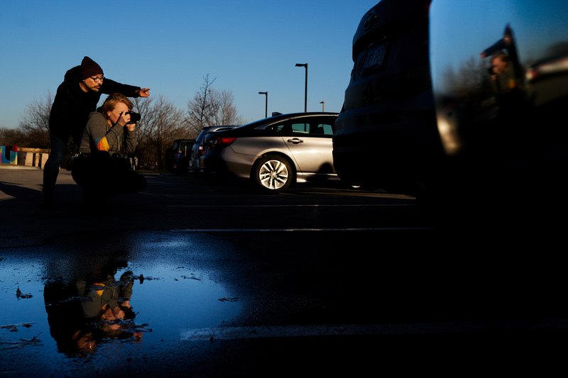 Photography coaching, A student is aiming her camera and a mentor directing the shot